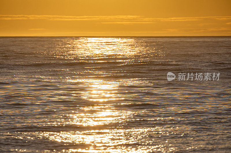 清晨平滑的海面，金色的光线和日出时戏剧性的天空