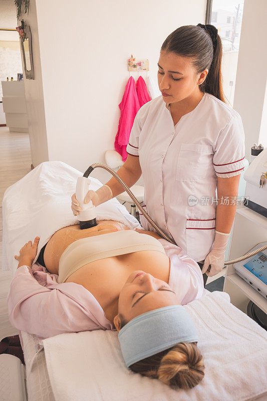垂直拍摄的女性物理治疗师做超声波空化治疗在水疗中心的女人