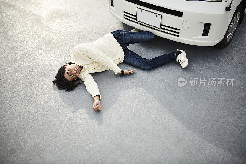 一个男人躺在车前