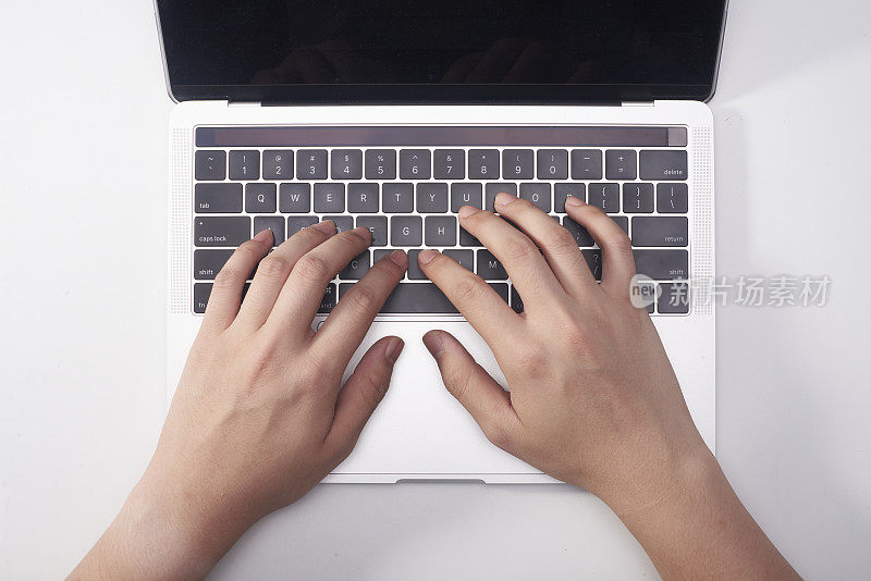 女性的手在笔记本电脑键盘上打字。白色背景。