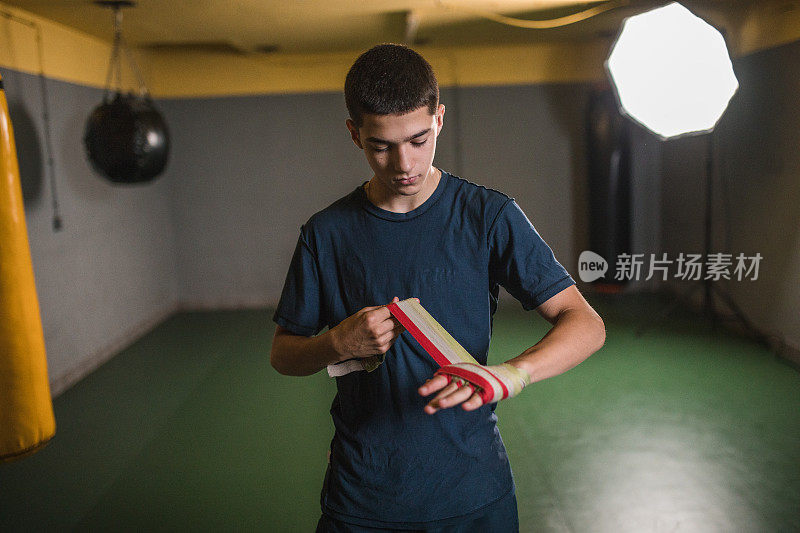 在拳击馆开始训练前，一名年轻的拳手在手上缠上防护绷带