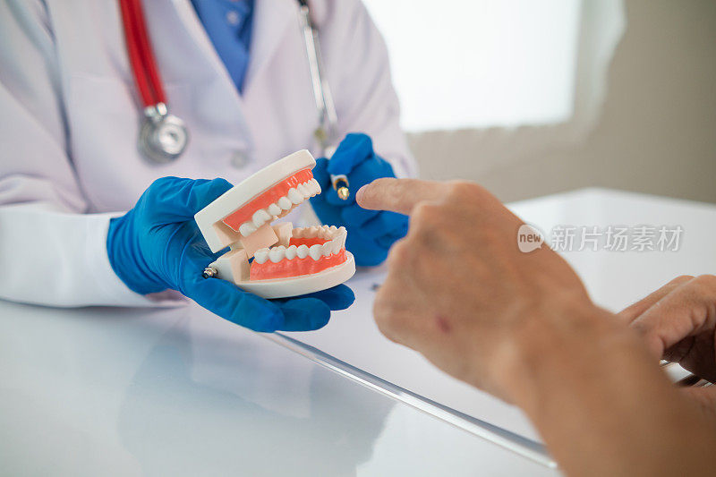 牙医会推荐治疗问题牙齿的方法，牙医也会建议患者在治疗完成后要照顾好自己的牙齿。牙医拿着假牙和病人交谈