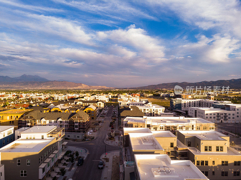 从空中俯瞰盐湖城的郊区景观:发展中的社区、熙熙攘攘的大道和商业中心，与远处的山脉和城市的活力相映衬。