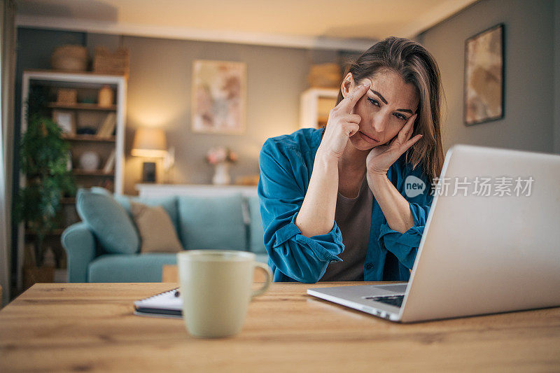 迷人的成年女商人独自坐在家里的办公室里，感觉压力很大