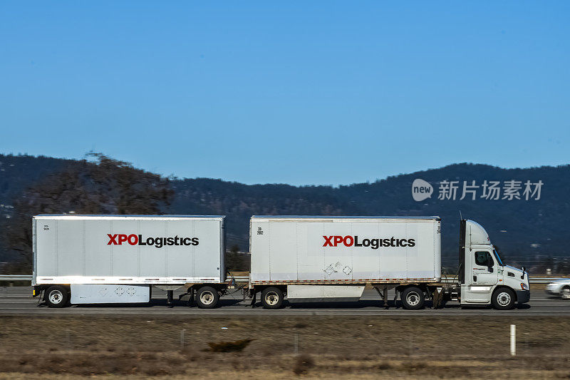 XPO物流半挂车，双挂车，在高速公路上行驶。