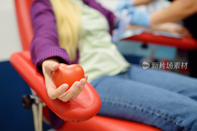 护士在现代实验室或医院里为年轻妇女采血作检查的护士年轻的成年女孩捐赠者在捐赠过程中手里拿着一个有弹性的心形球