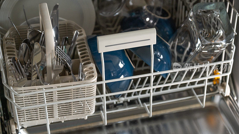 洗碗机有干净的盘子。厨房电器。盘子，叉子和杯子在洗碗机里。