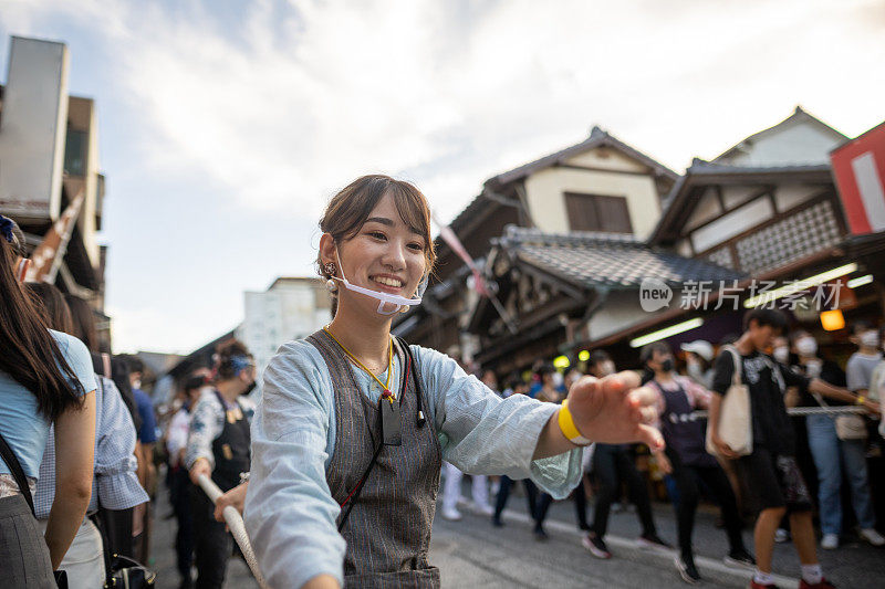 在日本传统的“松节”上，一名年轻女子拉着绳子将“大石”向前移动