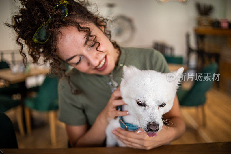 漂亮的少女在一家宠物友好的咖啡馆里喝咖啡