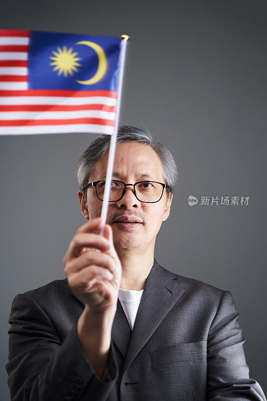 资深商人手持并挥舞着马来西亚国旗