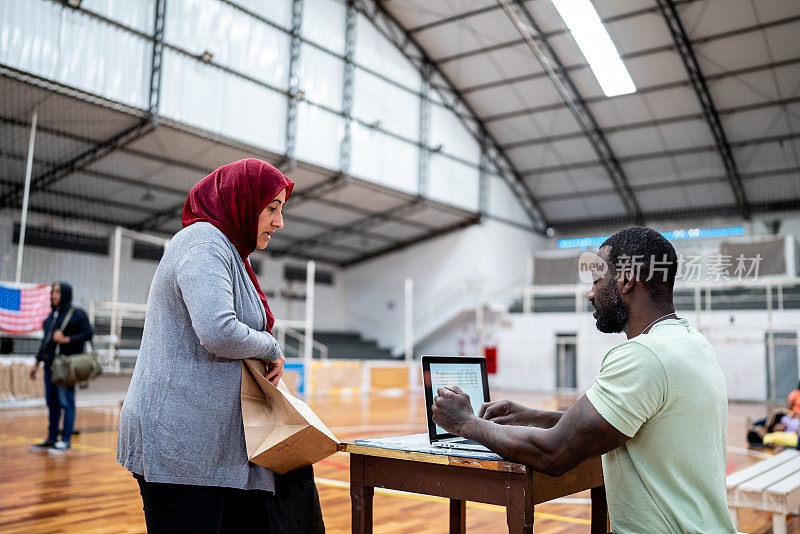 一名士兵在难民避难所使用笔记本电脑与一名难民妇女交谈