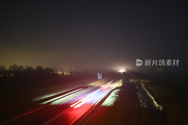 在冬天有雾的黑夜中行驶在道路上的车辆