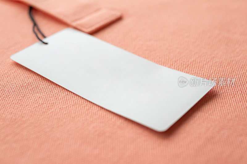 空白白色衣服标签标签上的粉红色织物纹理背景