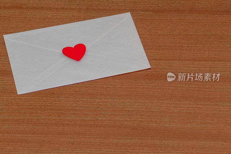 情人节的情书装在一个白色信封里，用红心在木头上封好