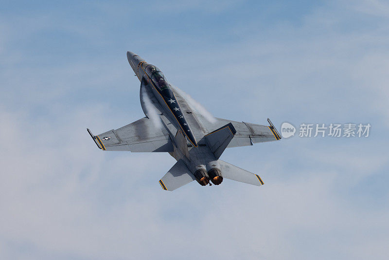 F-18大黄蜂高G机动的非常近的俯视图，在美丽的光线下，机翼根部有凝结条纹