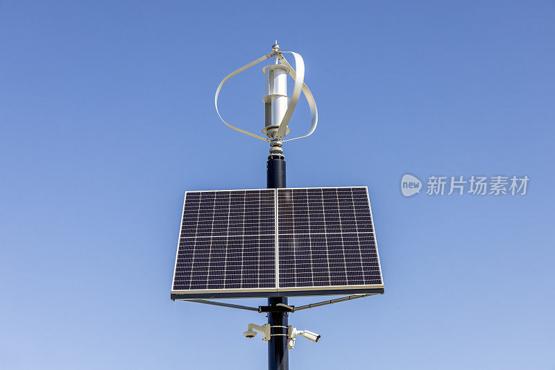 小型太阳能电池板与风力涡轮机，正面视图，蓝天背景与复制空间