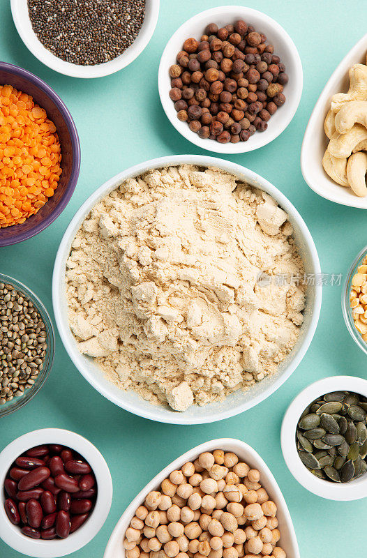 健康干豌豆蛋白粉和植物性蛋白质食品(豆类，扁豆，豆类，种子)蓝绿色背景。