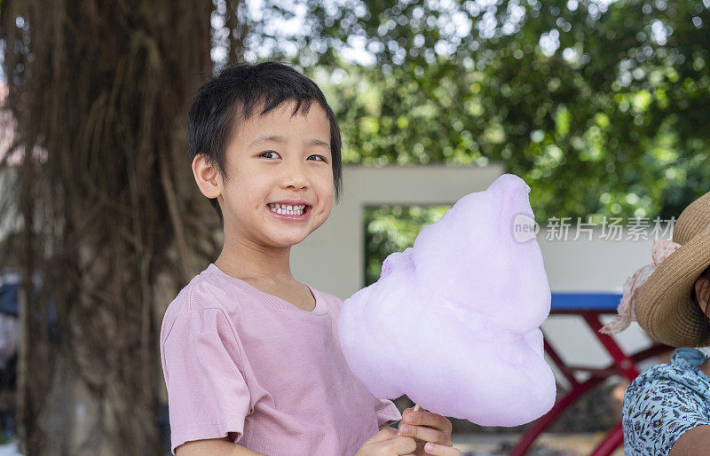 可爱的亚洲小女孩在户外吃棉花糖