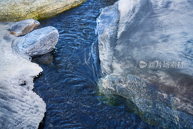 在挪威北部罗弗敦群岛的Kvalvika结冰的沙滩上，一条小溪的入海口。