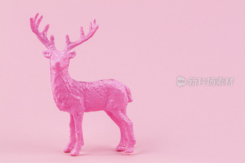 节日简约的圣诞背景。粉红色的背景上，一只粉红色的鹿。
