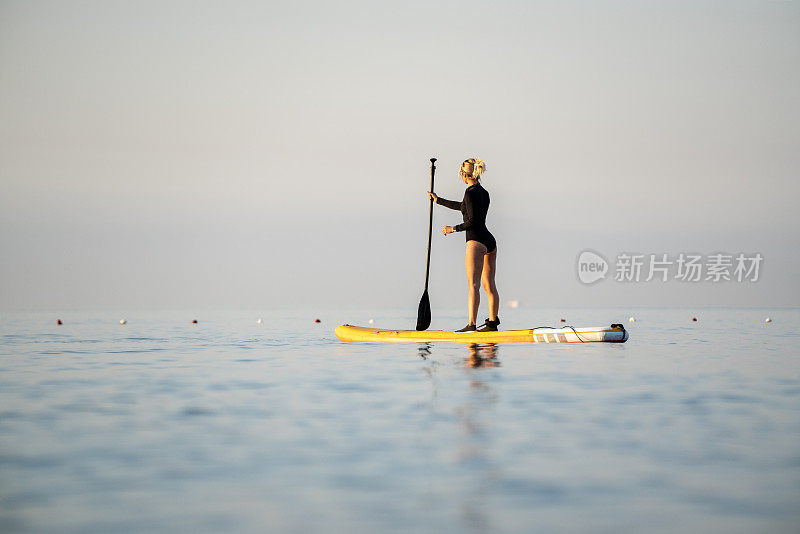 土耳其安塔利亚，科尼亚阿尔蒂海滩，年轻女子在日出时划桨登船