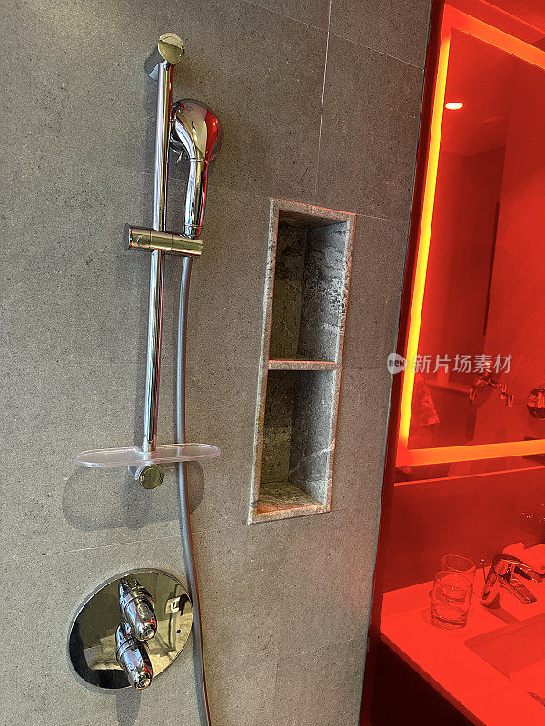 豪华浴室套房的镀铬墙淋浴装置和柔性管道图像，湿室红色玻璃淋浴隔断，棕色石墙砖
