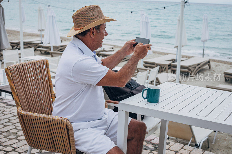 老游客在海边使用手机