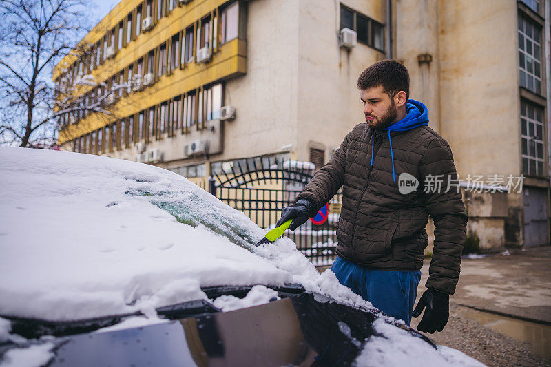 年轻人正在清除汽车上的积雪