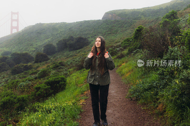 一名女子走在旧金山金门大桥的小山上