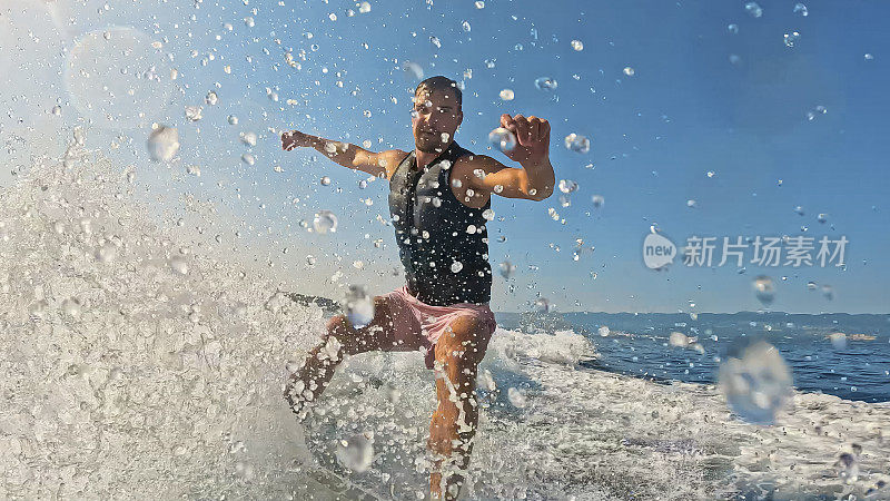 男子享受阳光明媚的一天，溅水，而在海上与令人振奋的行动