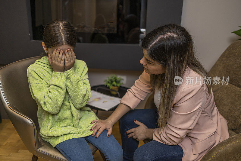 焦虑的母亲安慰哭泣的女儿。小女孩正在接受儿童心理学家的治疗