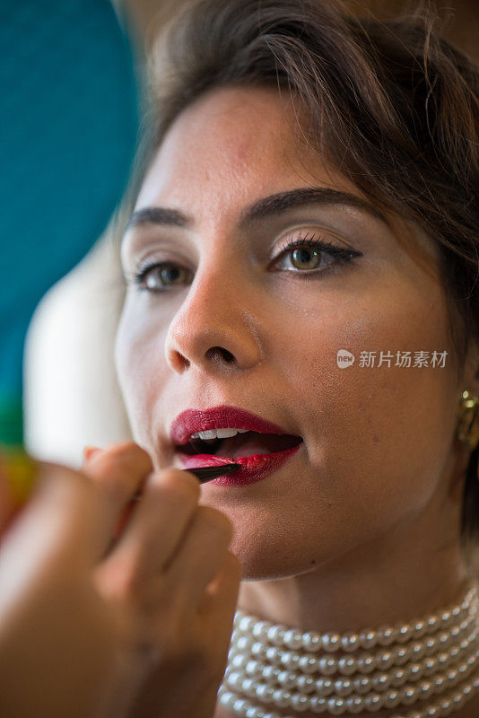 女人在嘴唇上涂口红的特写肖像