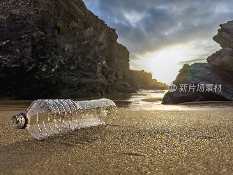 在葡萄牙的沙滩上，一个装满垃圾的空塑料瓶被疏忽地遗忘了