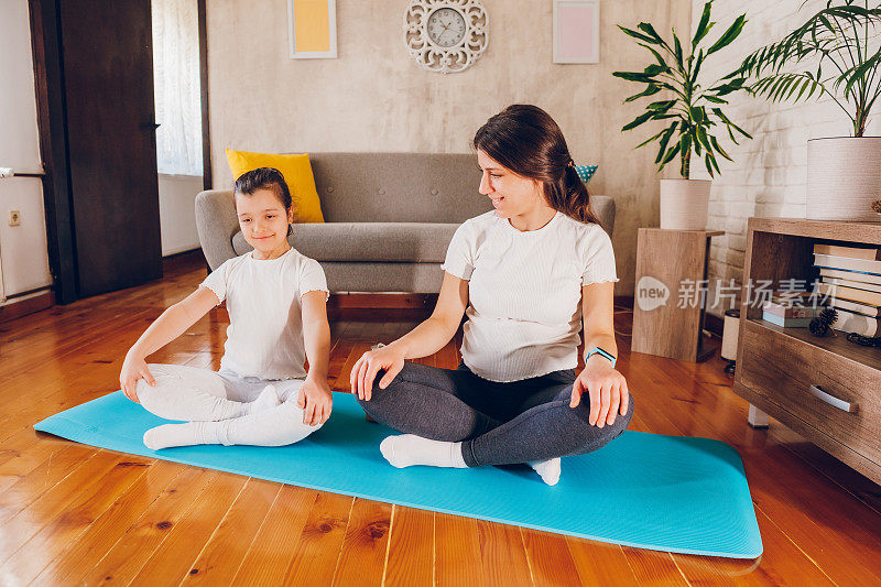 怀孕的母亲和她的女儿一起运动