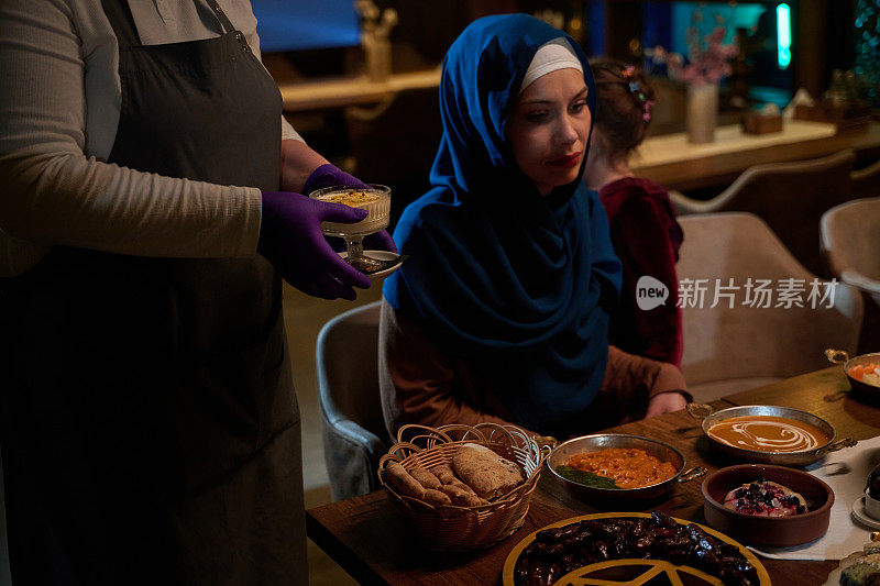 在一个温馨的场景中，一位专业厨师在斋月期间为一个欧洲穆斯林家庭提供开斋餐，在共同庆祝和感恩的时刻体现了文化的团结和烹饪的热情好客