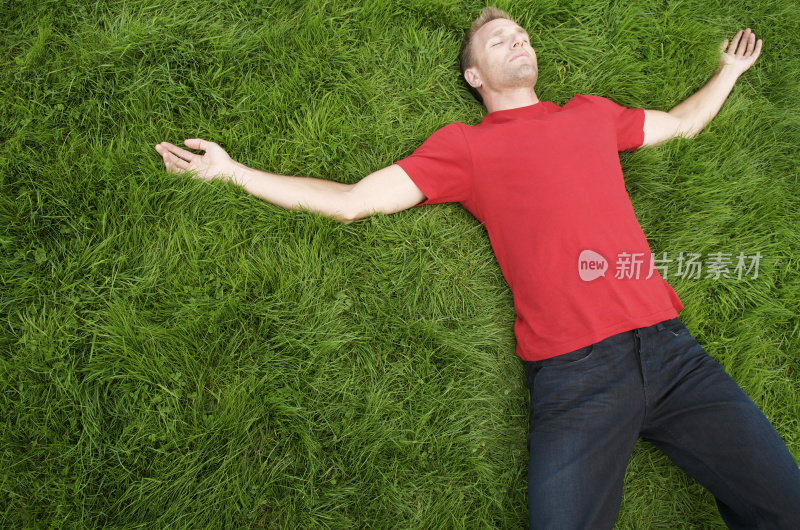 穿着红色t恤的年轻人在绿色草地上放松
