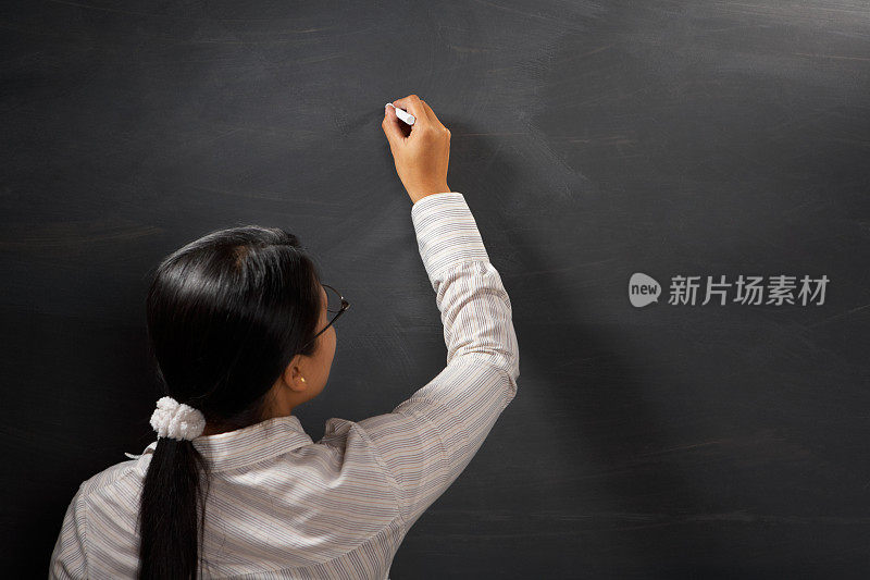老师拿着粉笔在空白的黑板上