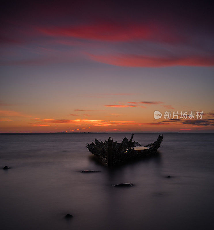 旧破船沉船，岸边，冰封的海，红色的夕阳背景。