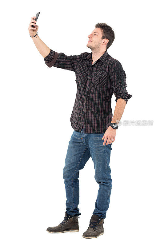 穿着牛仔裤和格子衬衫的休闲男子用手机拍照。