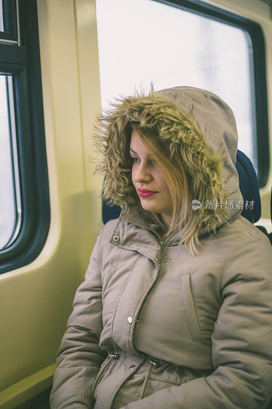 一个年轻女子坐在火车上望着窗外。