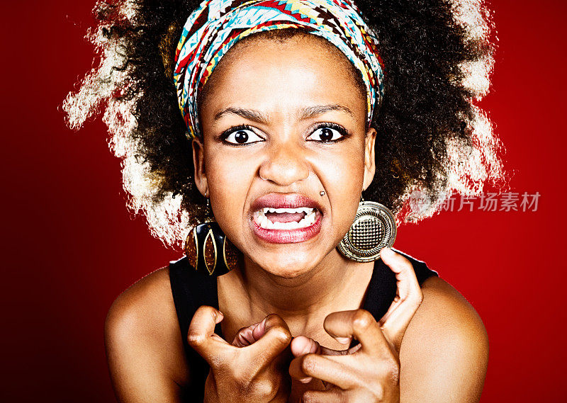 愤怒的年轻的非洲头发的女人紧握着拳头做鬼脸