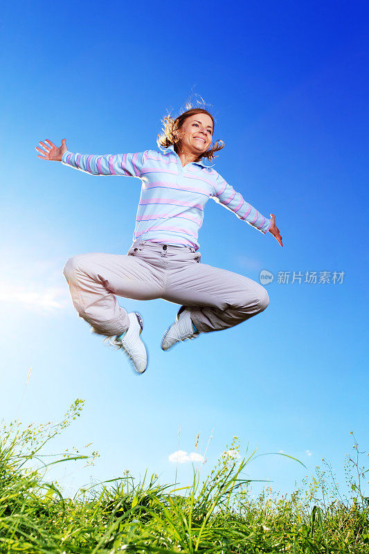 快乐的女人在蓝天上跳跃
