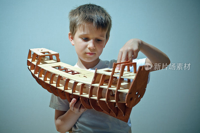 小男孩拿着古船的人造模型