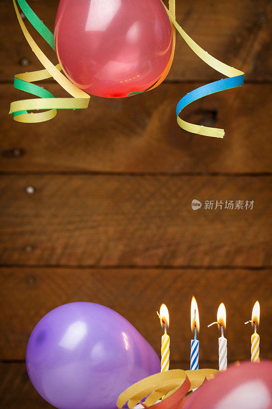 气球，蜡烛和彩带的木制背景