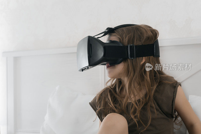 小女孩戴着VR眼镜坐在床上