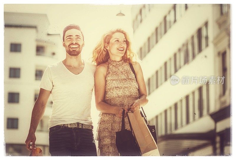 一对快乐的年轻夫妇在街上购物和散步