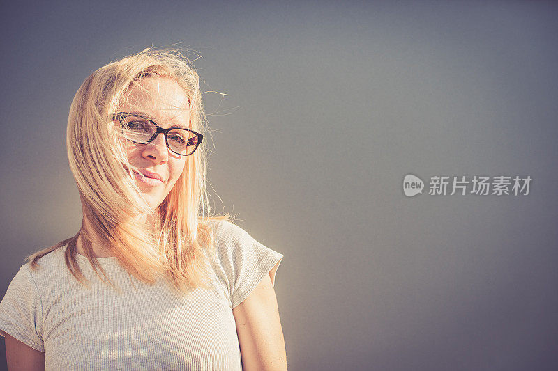 独立的年轻金发女人戴眼镜肖像户外