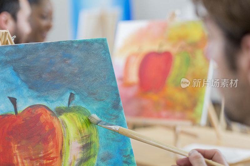 一位男艺术家在画布上画了一个苹果