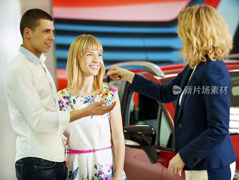 一对快乐的年轻夫妇买车。