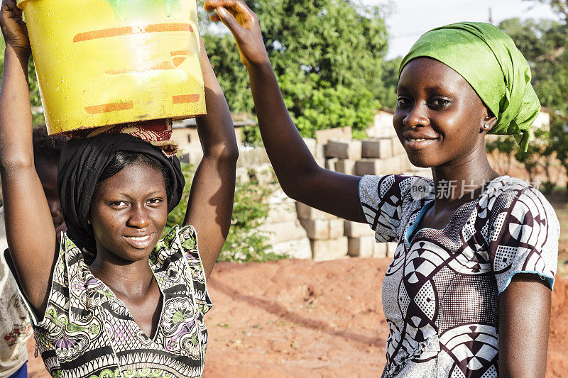 两个年轻的妇女在非洲挑水
